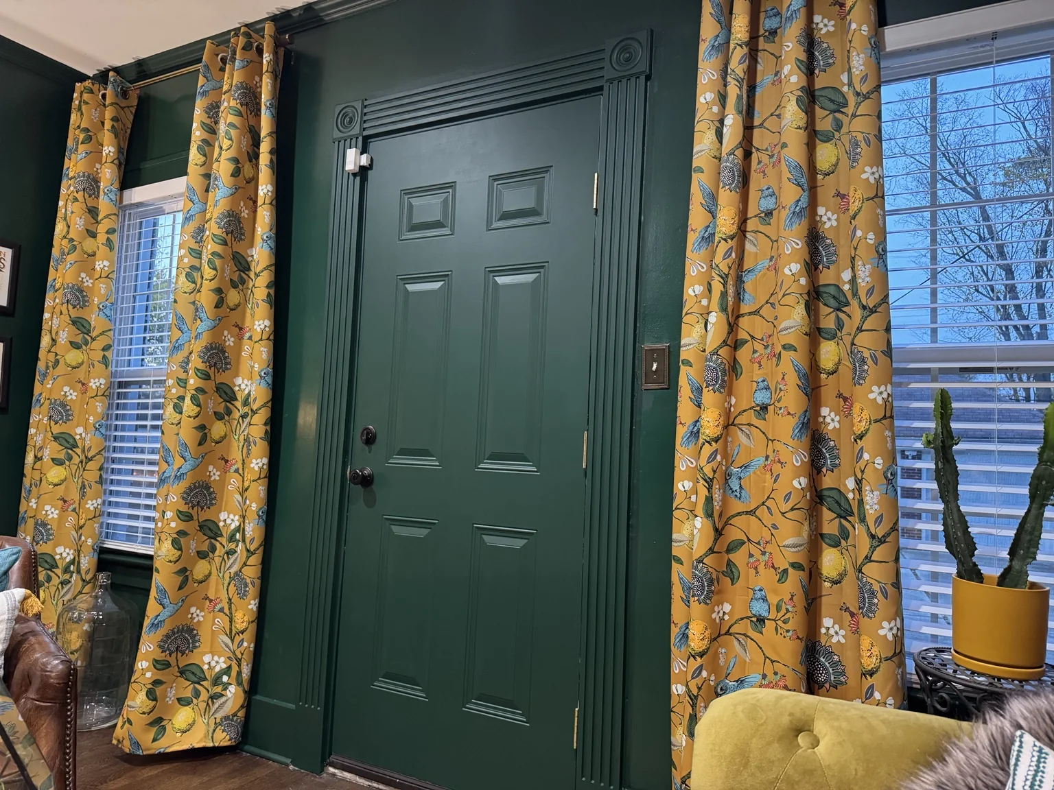 Green library door framed with decorative trim and mustard patterned curtains