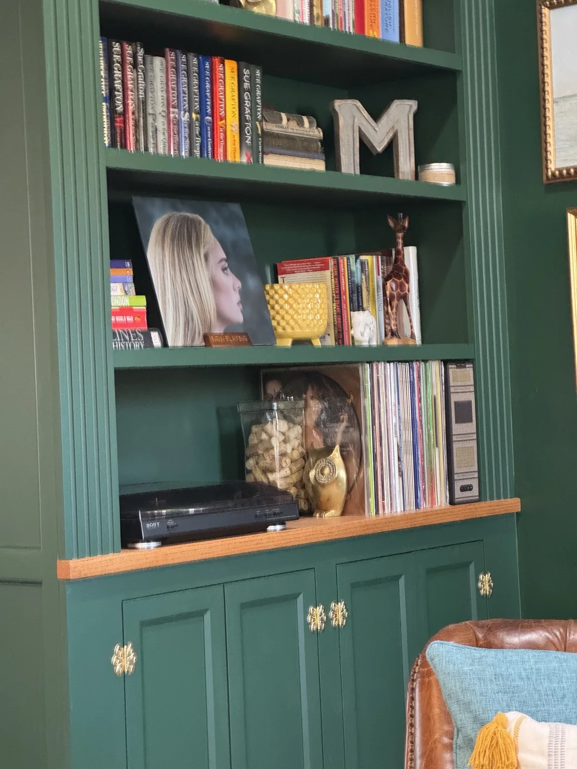 Styled library shelf with books, records, objects, and brass hardware